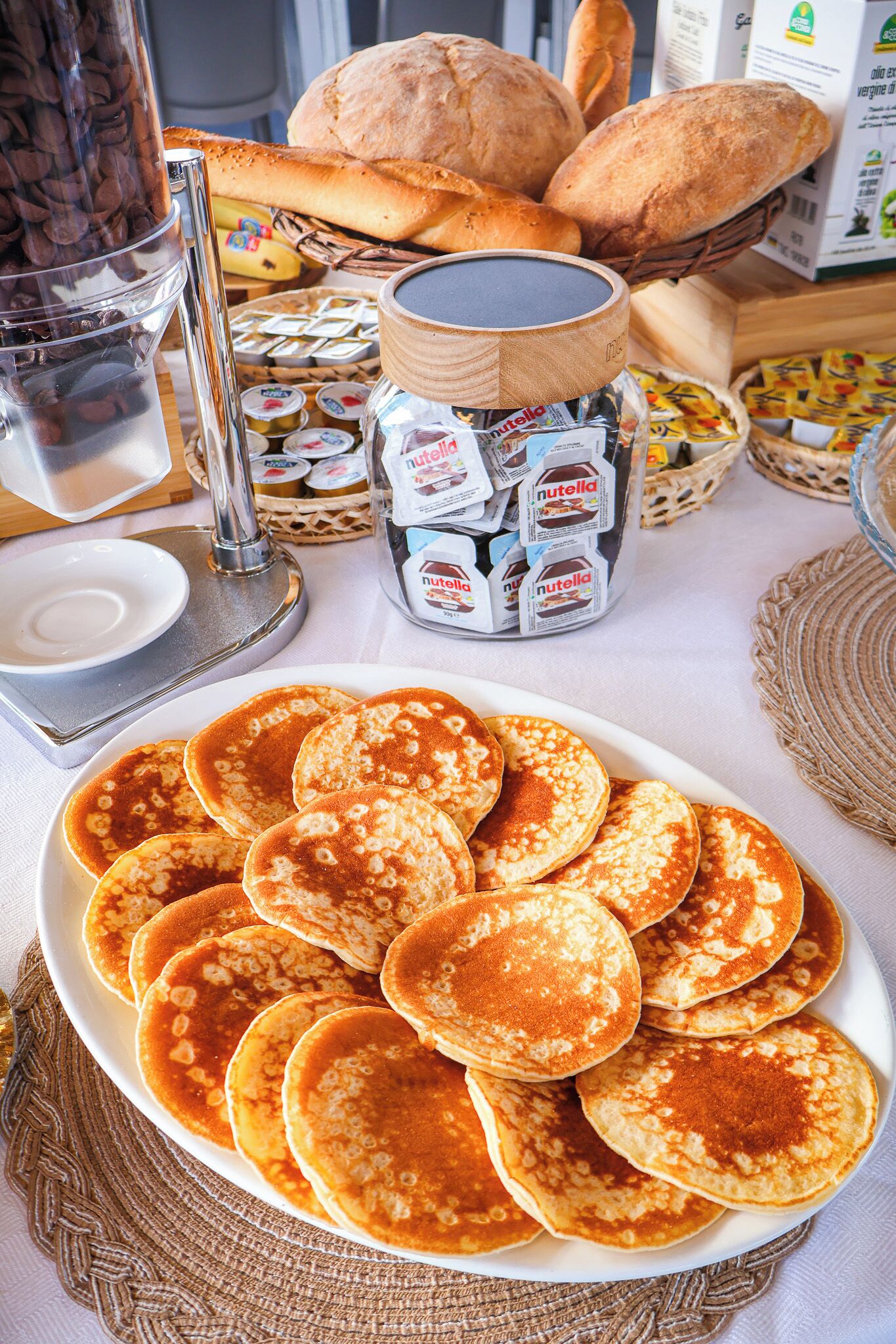 A breakfast table with pancakes, bread, and Nutella.