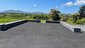 An open paved area with stone walls and a view of distant hills. - Paddy's Atlantic View! Home for 8 in Waterville! (Waterville)