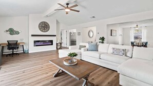 A modern living room with a white sofa, wooden coffee table, and a ceiling fan.