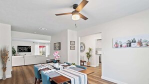 A modern dining area with a wooden table, blue chairs, and a ceiling fan.