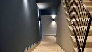 A staircase with a black metal railing, beige steps, and walls painted in blue and white. - Rich Boutique Hotel Vlore (Vlore)