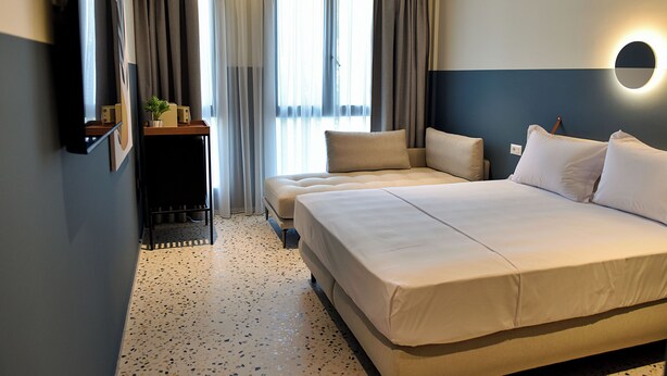 A hotel room with a large bed, a TV, a small table with a plant, and a window with curtains. - Rich Boutique Hotel Vlore (Vlore)