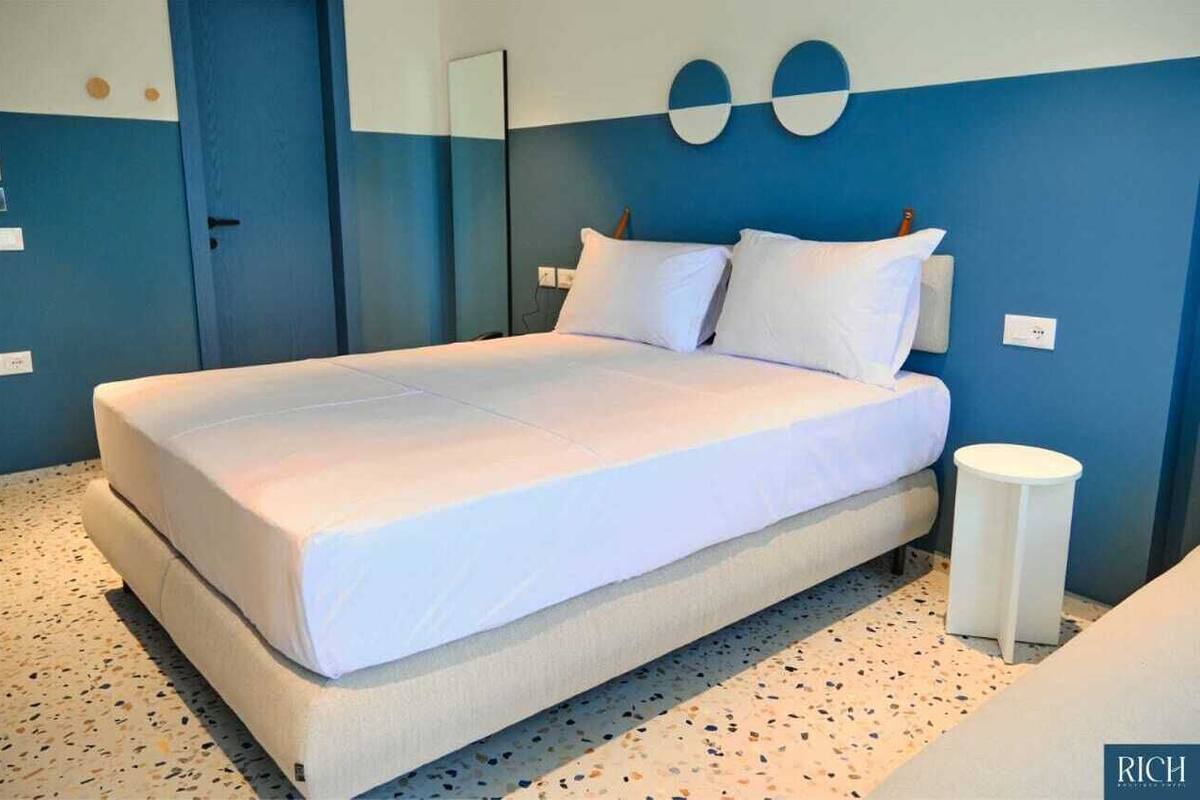 Ein modernes Schlafzimmer mit einem großen Bett, einem kleinen Nachttisch und einem an der Wand befestigten Spiegel.