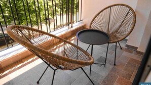 A balcony with two wicker chairs and a small table, a tiled floor, and a railing. - Rich Boutique Hotel Vlore (Vlore)