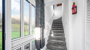 Un escalier, un extincteur fixé au mur, une fenêtre donnant sur l’extérieur et une porte avec un panneau en verre.