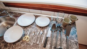A kitchen counter with various utensils and dishes, including plates, cups, and a sink. - POLOESTUDIOS (Zaratán)