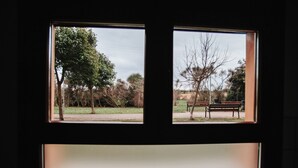 A view through a window with a bench and trees in the background. - POLOESTUDIOS (Zaratán)