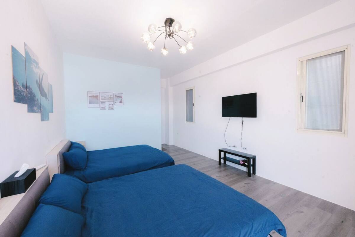 Une chambre d’hôtel moderne équipée de deux lits simples, d’un téléviseur à écran plat, d’une petite table et ornée d’œuvres d’art sur les murs.