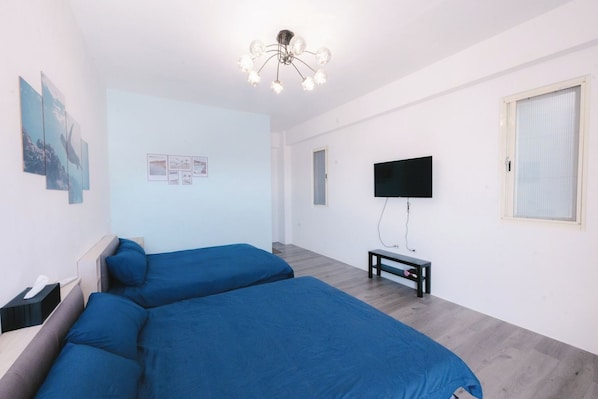 Habitación de hotel moderna con dos camas individuales, un televisor de pantalla plana, una mesita pequeña y obras de arte en las paredes.