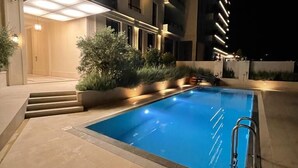 A nighttime view of a modern hotel with a swimming pool, outdoor lighting, and a well-maintained garden area. - CASA AL MARE by Moskva (Becici)