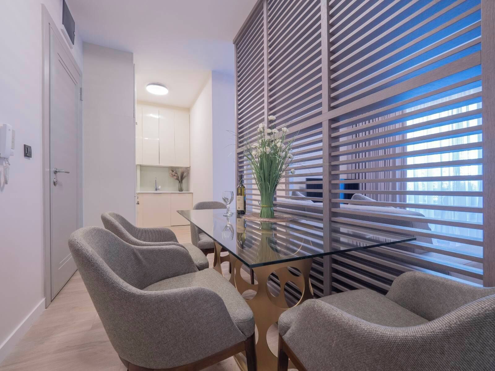 Un espace repas moderne avec une table en verre et quatre chaises grises à revêtement.