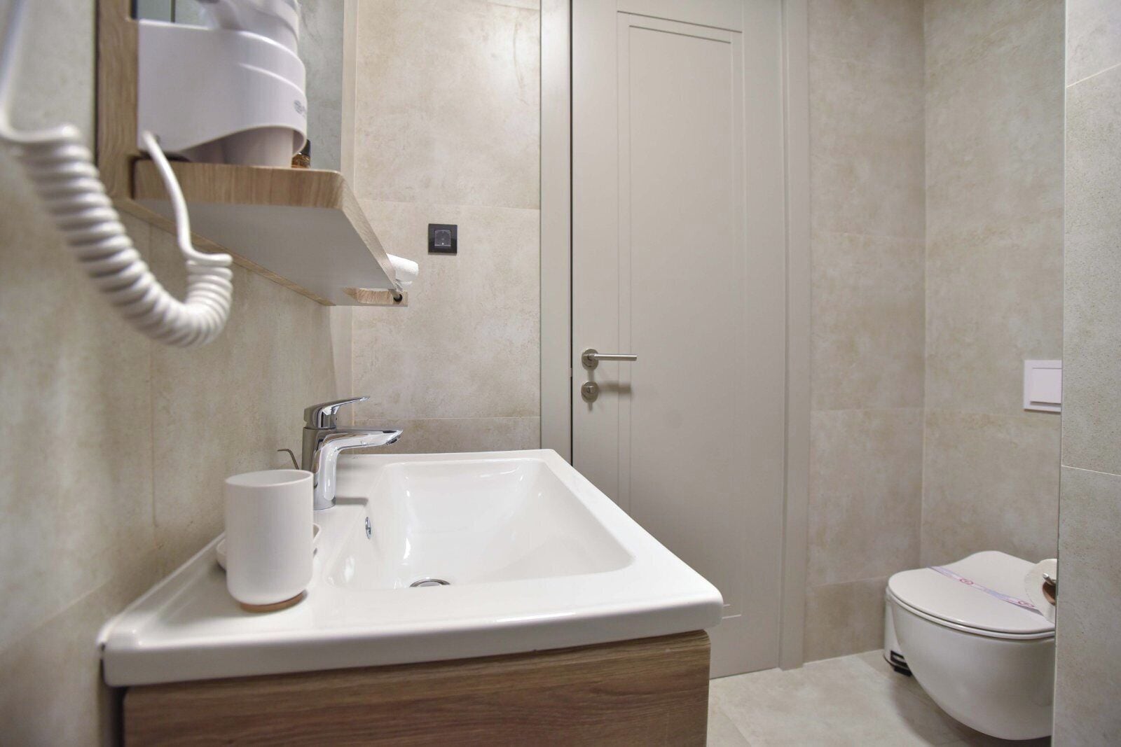 A bathroom with a white sink, a mirror, a towel rack, and a toilet.