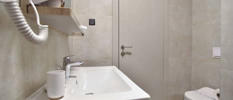 A bathroom with a white sink, a mirror, a towel rack, and a toilet.