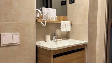 A modern bathroom with a wooden vanity, a white sink, and a mirror above it. There is a towel hanging on the wall and a toilet with a white lid.