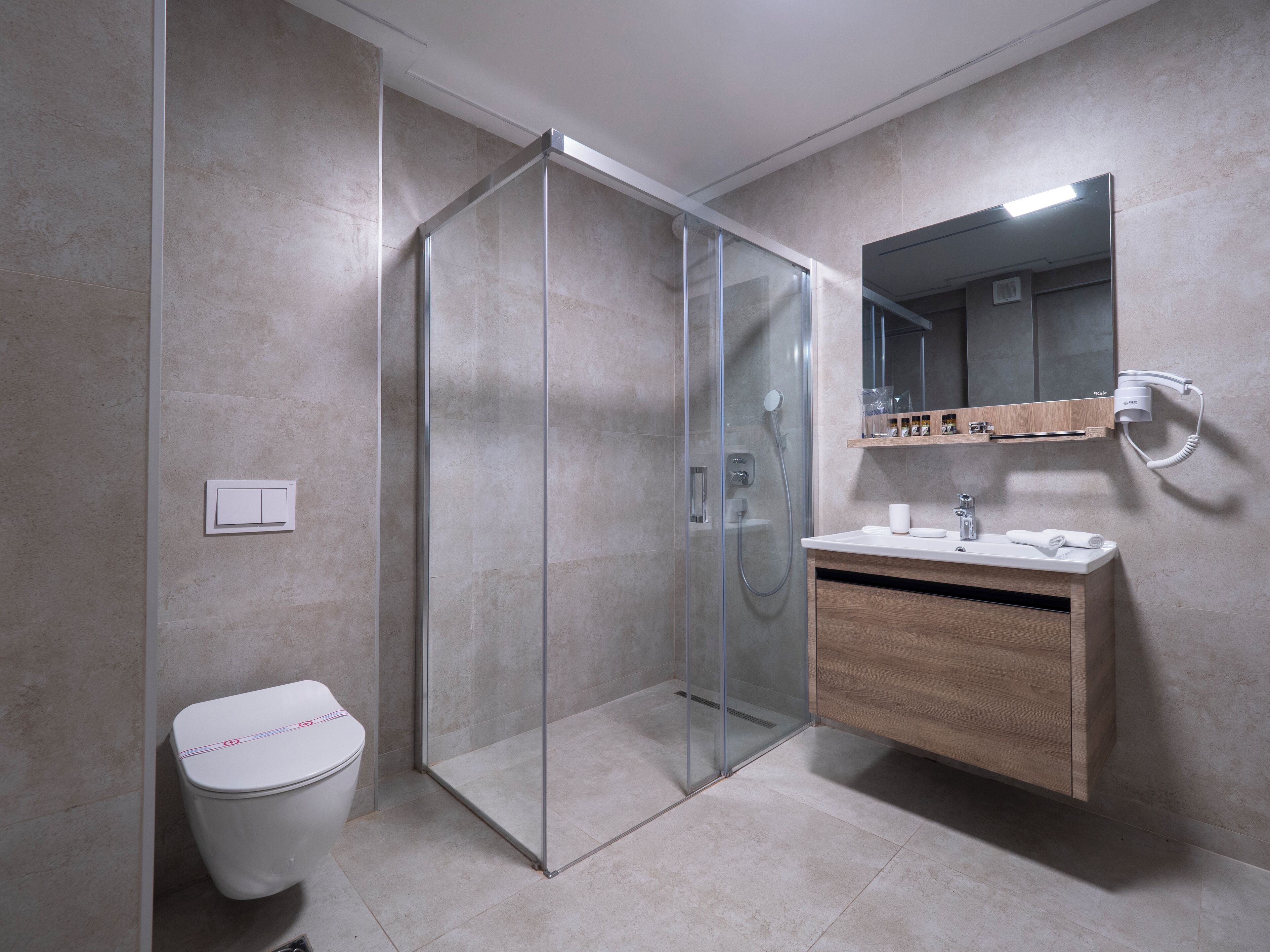 A modern bathroom with a glass-enclosed shower, a wooden vanity, and a mirror above the sink.