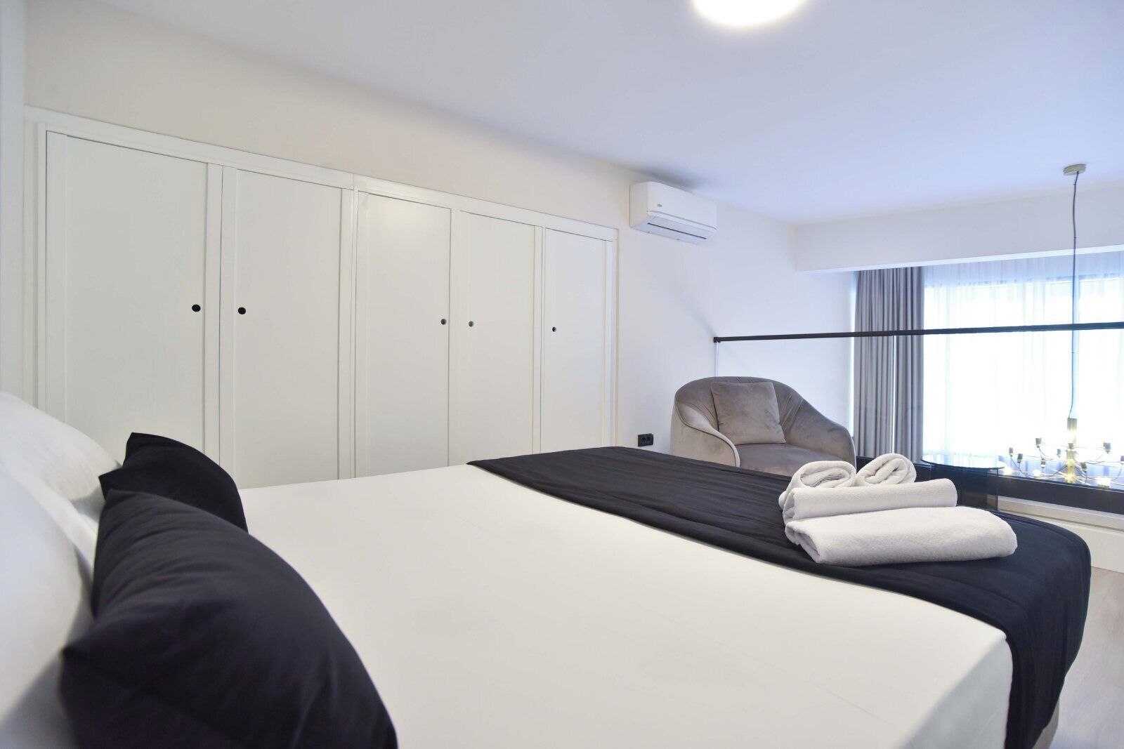 A hotel room with a large bed, a chair, and a window with curtains.