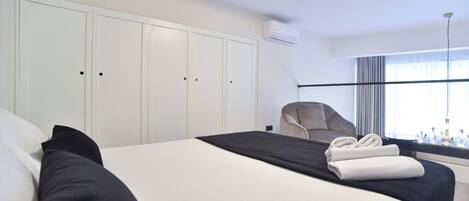 A hotel room with a large bed, a chair, and a window with curtains.