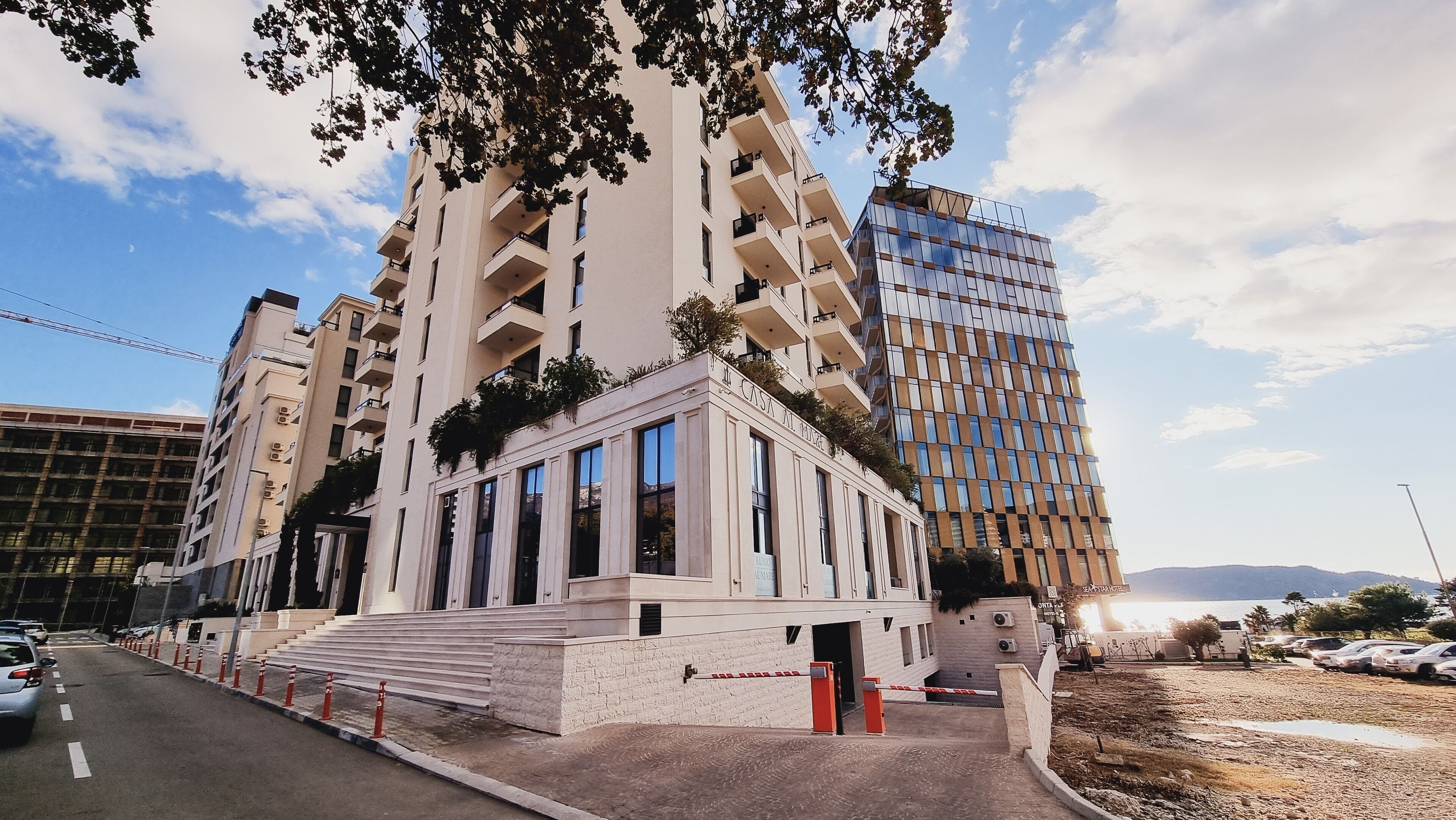 Um hotel moderno com entrada imponente, várias varandas e vista para a paisagem urbana ao redor.