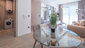 A modern living room with a glass coffee table, a beige sofa, and a dining area with a glass table. - CASA AL MARE by Moskva (Becici)