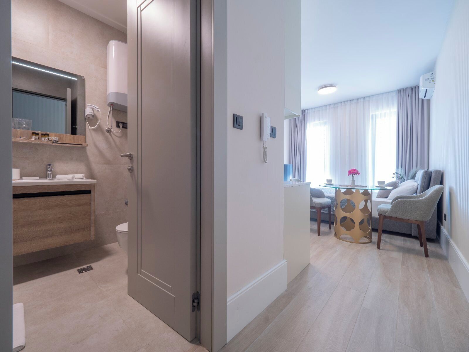 Et moderne hotelværelse med badeværelse, spiseplads og opholdsområde.