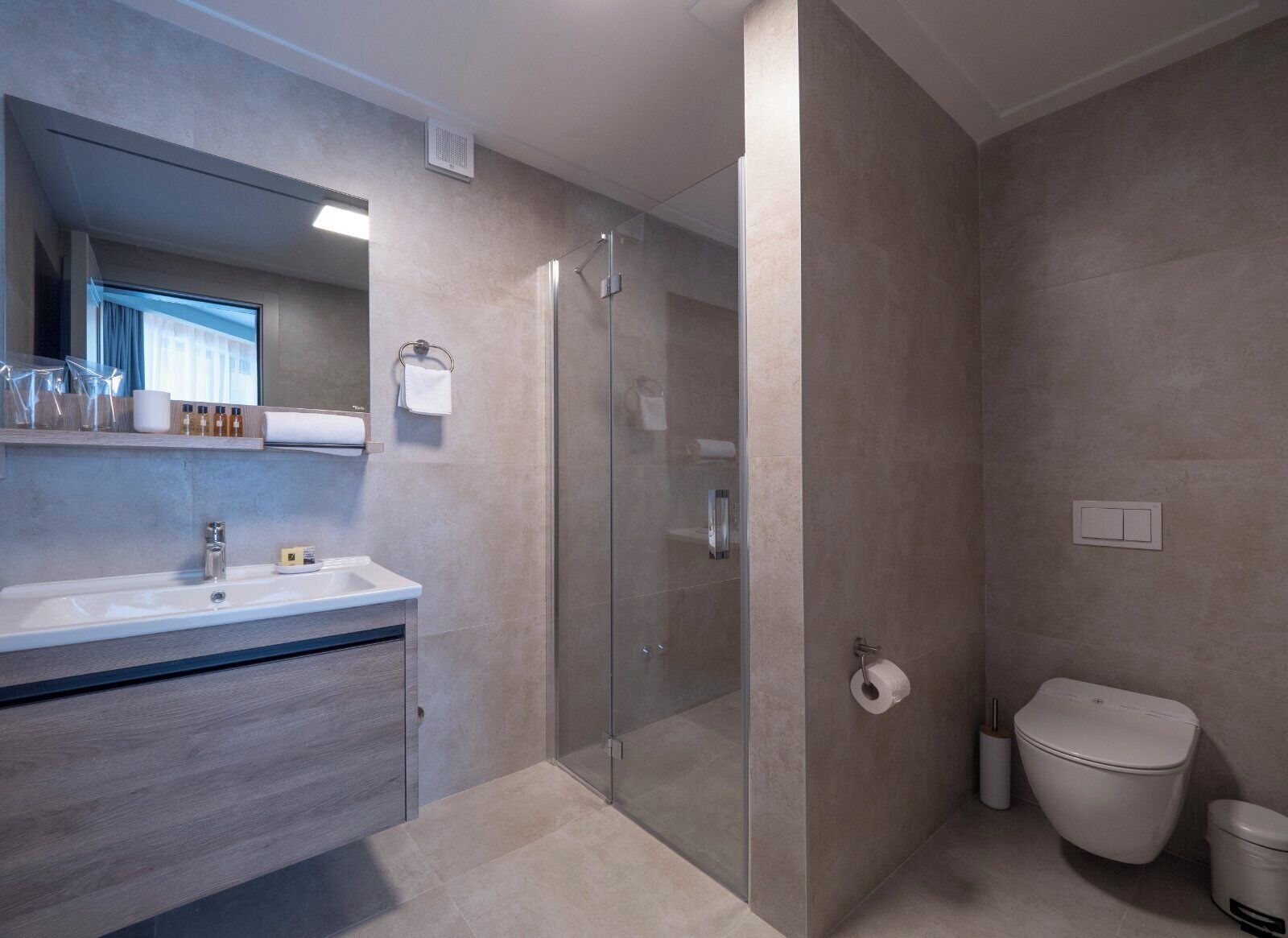 A modern bathroom with a glass-enclosed shower, a sink with a mirror, and a toilet.