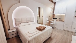 A modern hotel room with a large bed, a desk, and a kitchenette. - CASA AL MARE by Moskva (Becici)