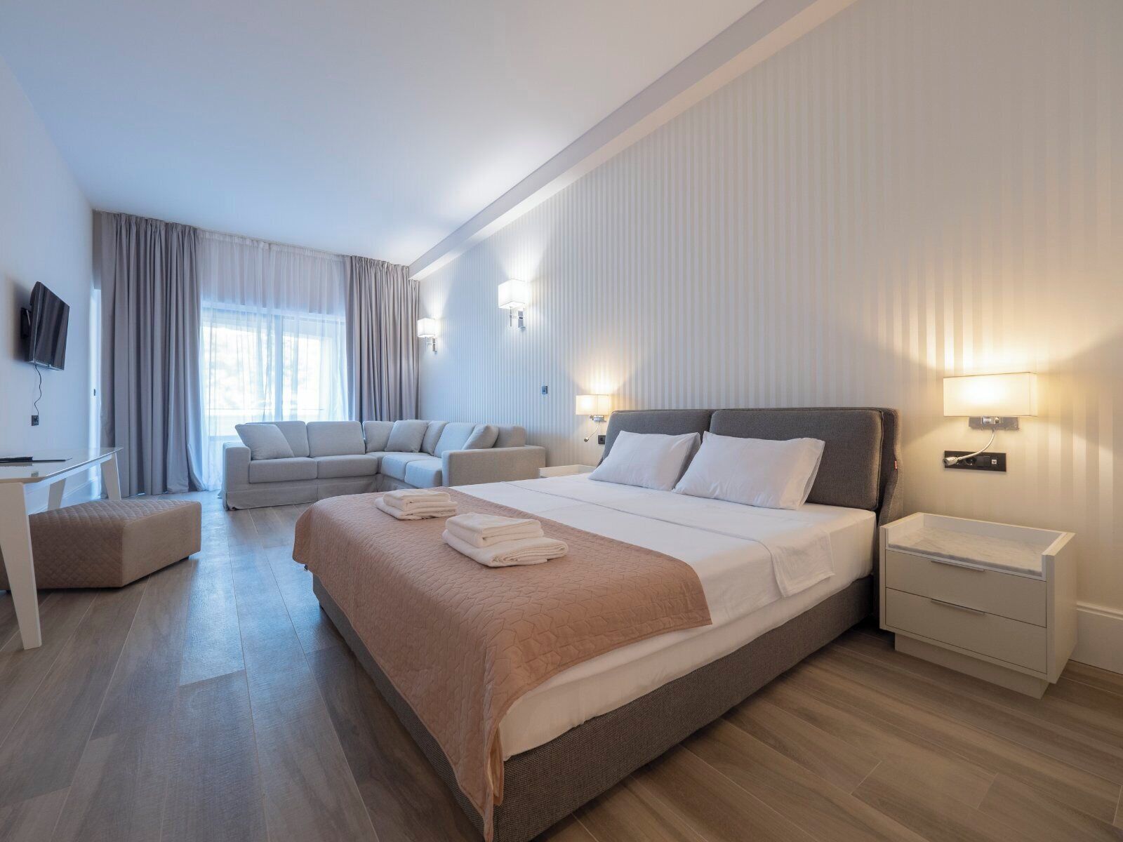 Una habitación de hotel moderna con una cama grande, un sofá, un escritorio y un televisor.