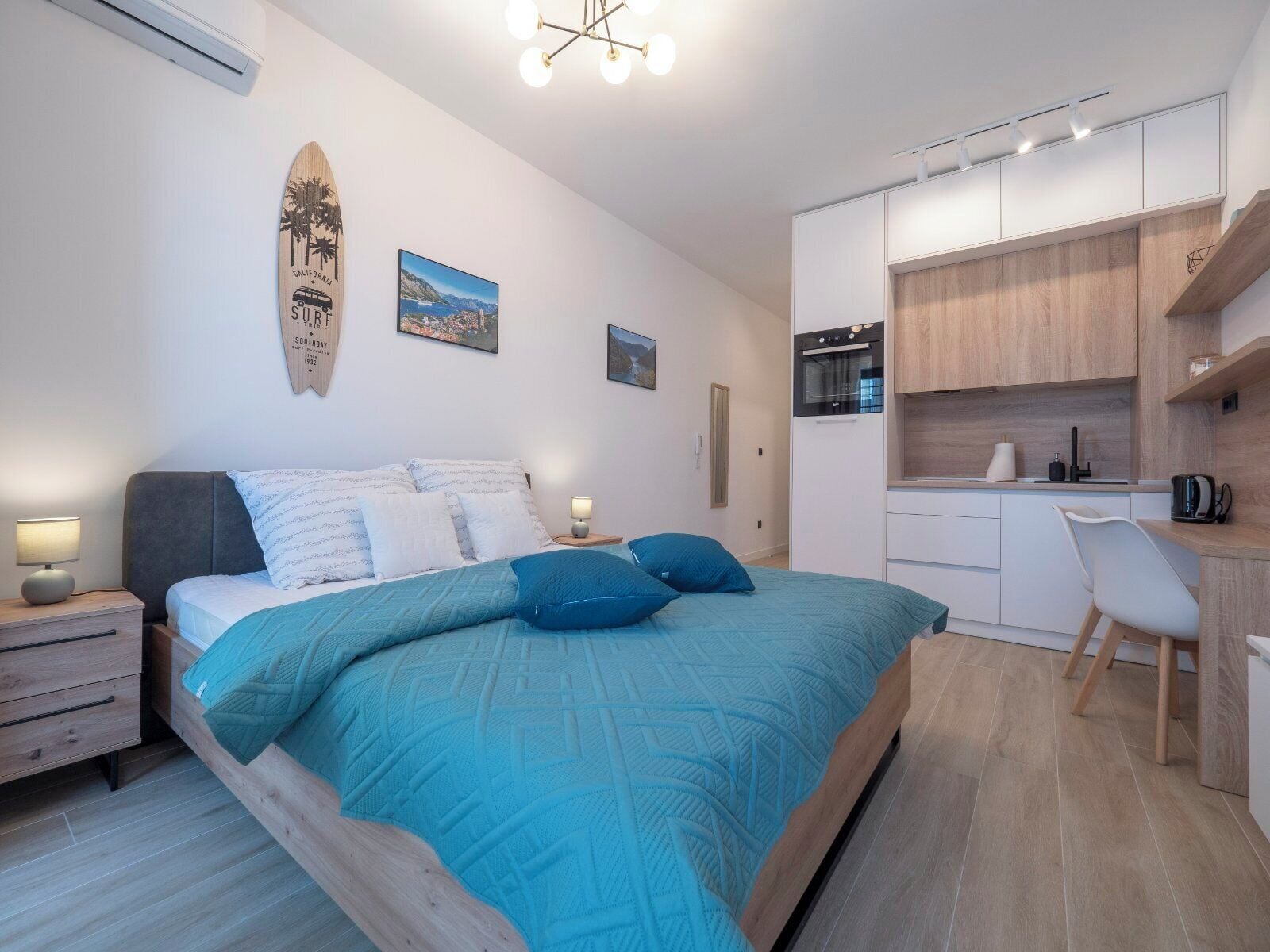 Un dormitorio con cama, mesitas de noche, escritorio y kitchenette.
