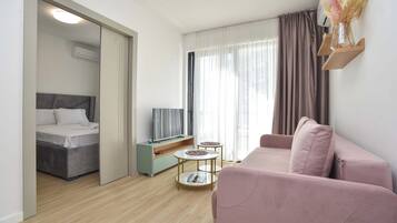 Una sala de estar moderna con una cama, un sofá, un televisor y una mesita.