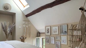 A bedroom with a bed, a macrame hanging chair, and framed artwork on the walls. - Charming house close to the Loire châteaux (Baule)
