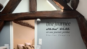 A staircase with a wooden railing, a wall with a French quote, and a teal scooter painting. - Charming house close to the Loire châteaux (Baule)