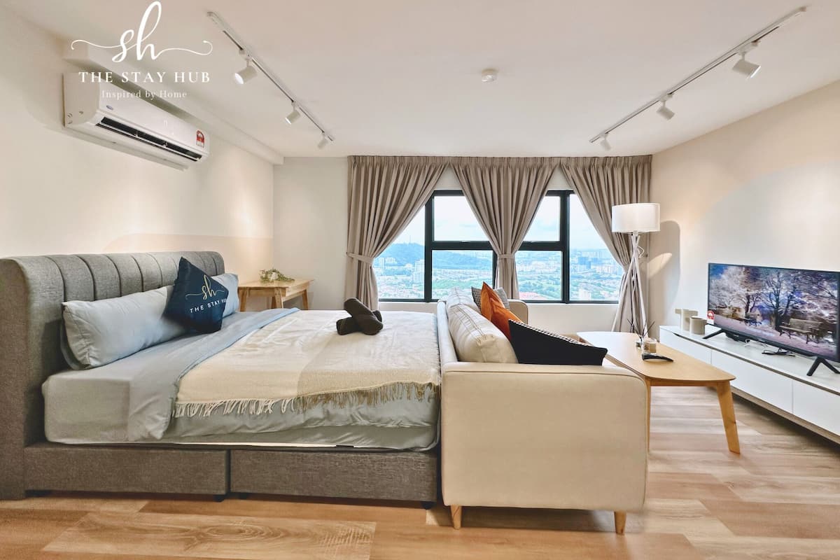 Een moderne hotelkamer met een bed, bank, televisie en uitzicht op de stad.
