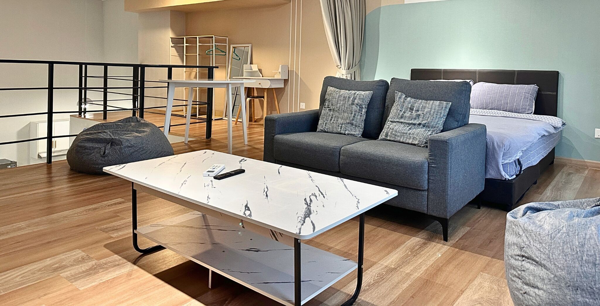 A modern living room with a grey sofa, a white marble coffee table, and a grey bean bag.