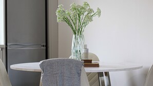 A round table with a vase of white flowers, a bottle, and a book. - Modern Apex Flat / King Bed/3 Guests/ Parking/WiFi (Argyll and Bute Council)