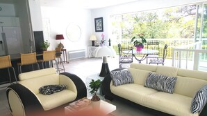 Ein Wohnzimmer mit einer Couch, Sesseln, einem Couchtisch und einem Essbereich mit Tisch und Stühlen.
