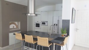 Eine moderne Küche mit einer zentralen Kochinsel, Barhocker, integrierten Geräten und einer Pendelleuchte.