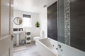 A modern bathroom with a bathtub, toilet, and sink.