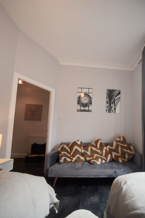 Relax in this stylish living room with a sofa, artworks, and a door leading to another area.