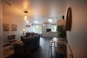 Relax in a spacious living area with a sofa, dining table, and kitchen in the background.
