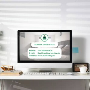 A computer monitor displaying information for Aurora Short Stays, including a mobile number, email, and website.