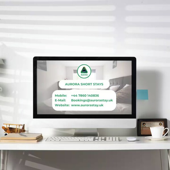 A computer monitor displaying information for Aurora Short Stays, including a mobile number, email, and website.