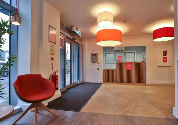 A reception area with a red chair, a reception desk, and three pendant lights.
