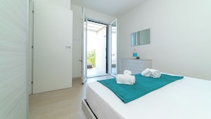 Een slaapkamer met een bed, een badkamer en een balkon.