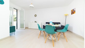 Een moderne eethoek met blauwgroene stoelen, een witte tafel en een donkere bank.
