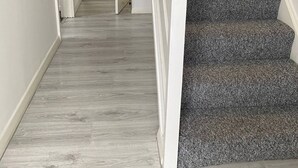 A staircase with carpeted steps leading to a kitchen area with wooden cabinets and a tiled backsplash.