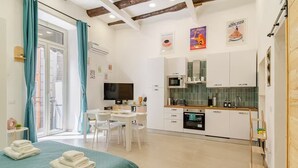 En moderne lejlighed med spiseområde, køkken og en balkon med gardiner.
