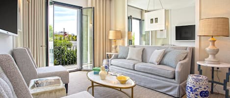 A modern living room with a grey sofa, a round coffee table, and a blue and white patterned ottoman.