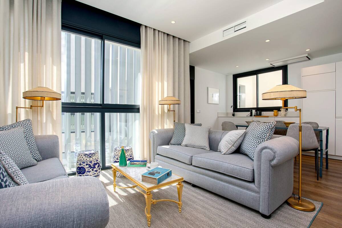 A modern living room with a grey sofa, two armchairs, a coffee table, and two floor lamps.