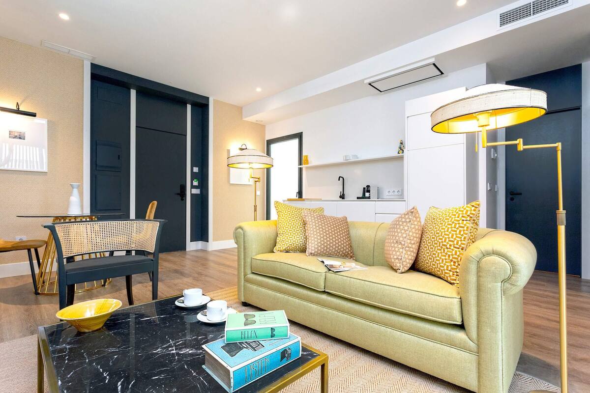 A modern living room with a sofa, coffee table, and a dining area with a chair and table.