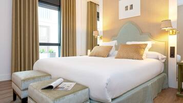 A neatly made bed with patterned pillows, a side table with a lamp, and a window with curtains.